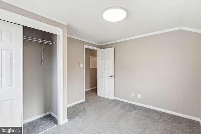 unfurnished bedroom with a closet, ornamental molding, baseboards, and carpet floors