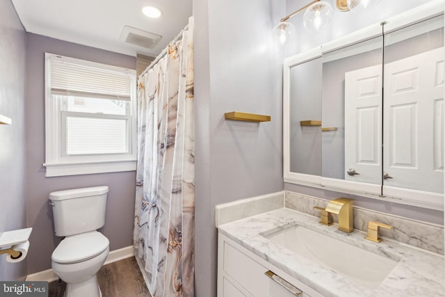 bathroom with vanity, wood finished floors, visible vents, baseboards, and toilet