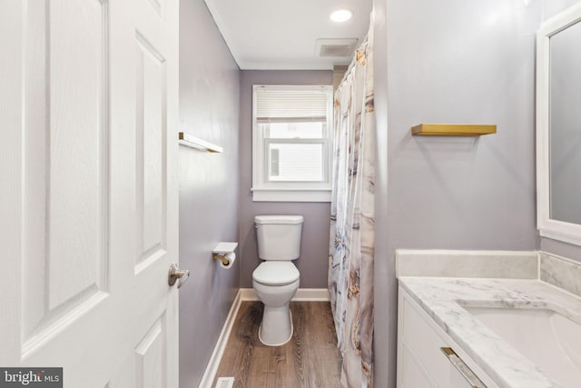 full bathroom featuring toilet, vanity, baseboards, and wood finished floors