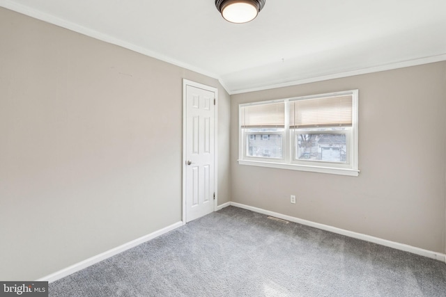 carpeted empty room featuring baseboards and crown molding