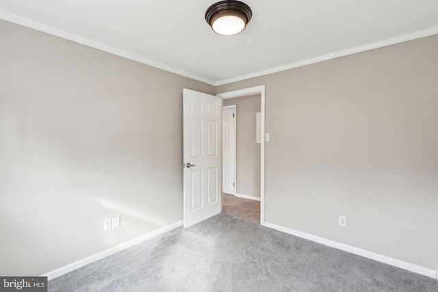 carpeted empty room featuring baseboards and ornamental molding