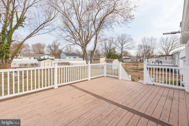 wooden terrace featuring a storage unit, a residential view, an outbuilding, and a fenced backyard