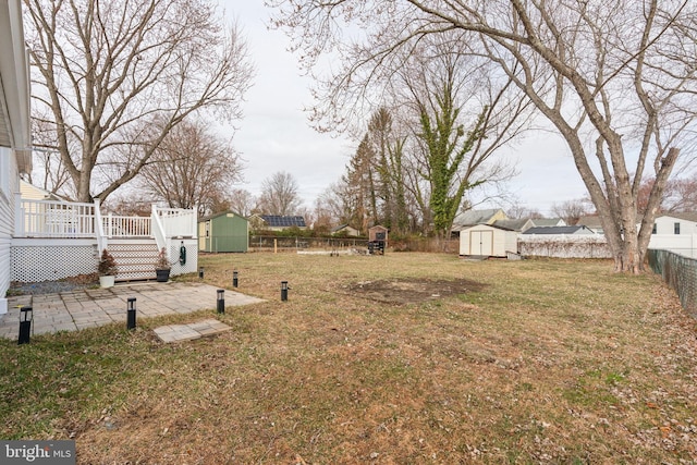 view of yard featuring a deck, a storage unit, a fenced backyard, and an outdoor structure