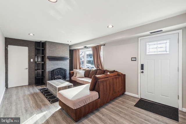 living room featuring visible vents, recessed lighting, light wood-style floors, a fireplace, and baseboards