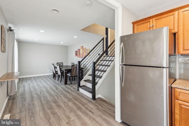 kitchen with tasteful backsplash, freestanding refrigerator, baseboards, and wood finished floors