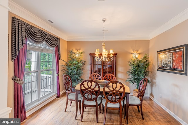 dining room featuring a chandelier, light wood-type flooring, baseboards, and ornamental molding