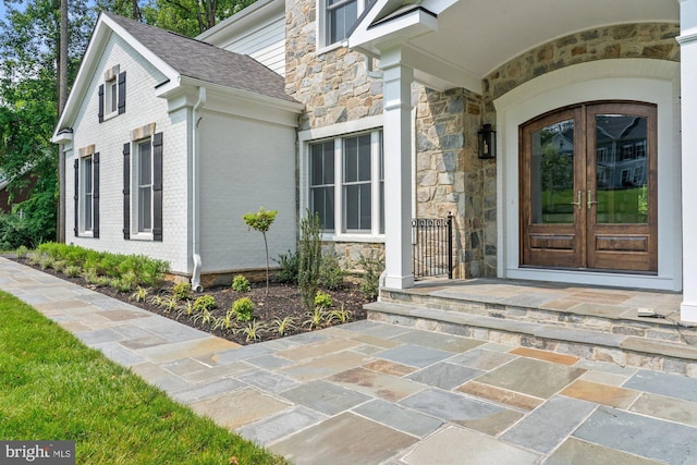 3006 Weber Pl, Oakton, VA 22124 - view of exterior entry featuring french doors, stone siding, a shingled roof, and brick siding