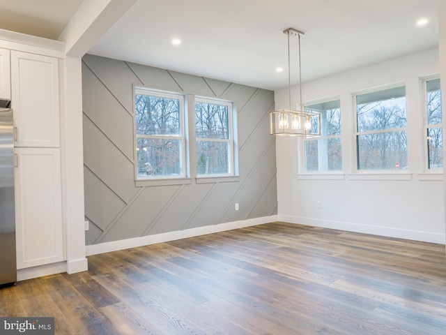 unfurnished dining area featuring a notable chandelier, recessed lighting, baseboards, and wood finished floors