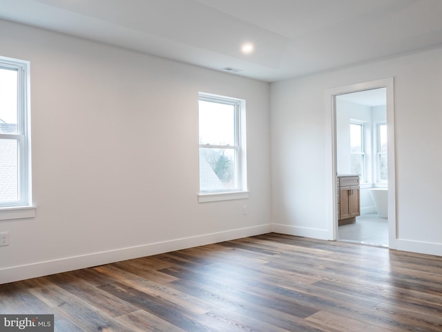 unfurnished bedroom featuring baseboards, ensuite bath, and wood finished floors