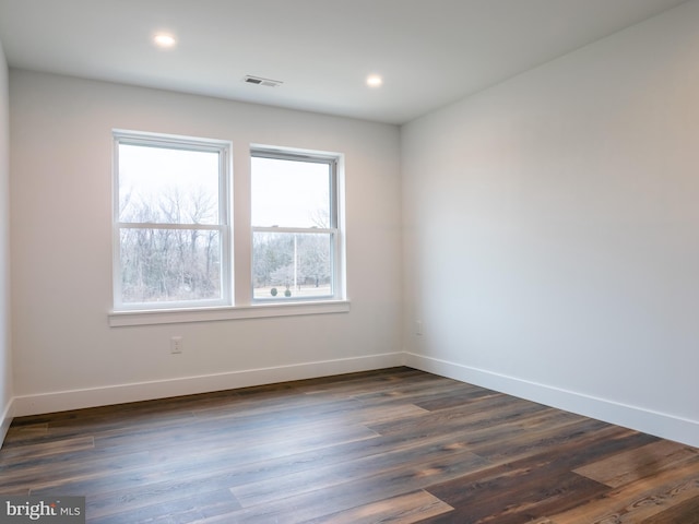 spare room with recessed lighting, visible vents, baseboards, and dark wood finished floors