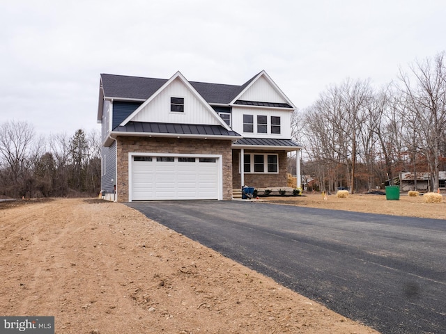 view of front of home with aphalt driveway, metal roof, an attached garage, and a standing seam roof