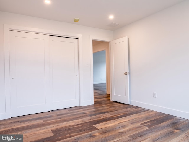 unfurnished bedroom with recessed lighting, wood finished floors, a closet, and baseboards