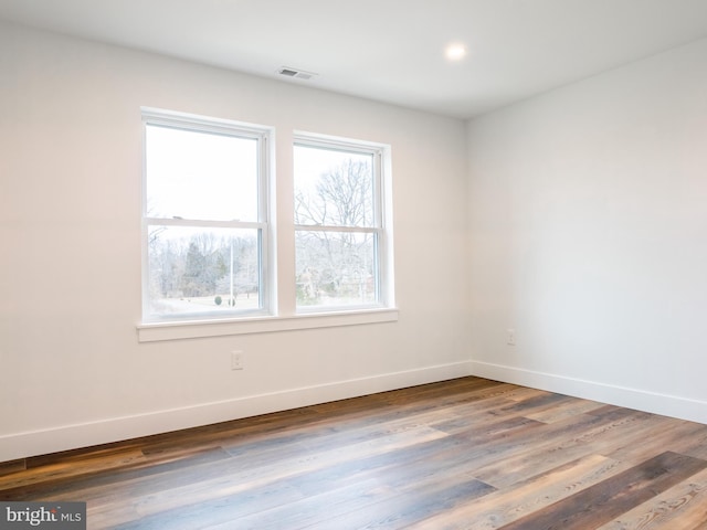 unfurnished room featuring visible vents, baseboards, and wood finished floors