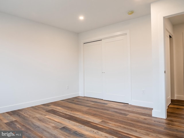 unfurnished bedroom featuring dark wood-type flooring, recessed lighting, baseboards, and a closet