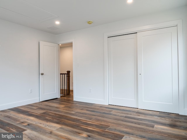 unfurnished bedroom featuring a closet, baseboards, and dark wood-style flooring