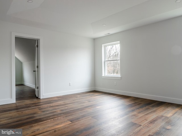 empty room with visible vents, baseboards, and dark wood finished floors