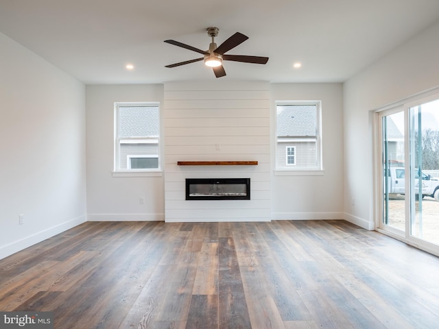 unfurnished living room with wood finished floors, recessed lighting, a large fireplace, baseboards, and ceiling fan