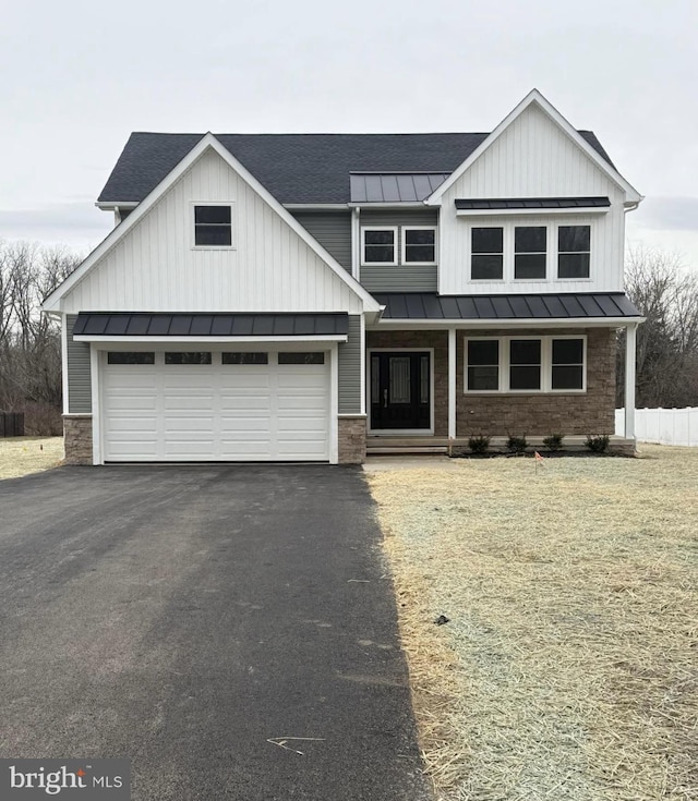 modern farmhouse featuring a standing seam roof, an attached garage, a shingled roof, aphalt driveway, and metal roof