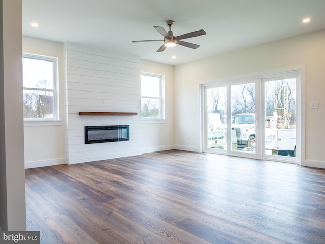 unfurnished living room featuring ceiling fan, baseboards, wood finished floors, and a fireplace