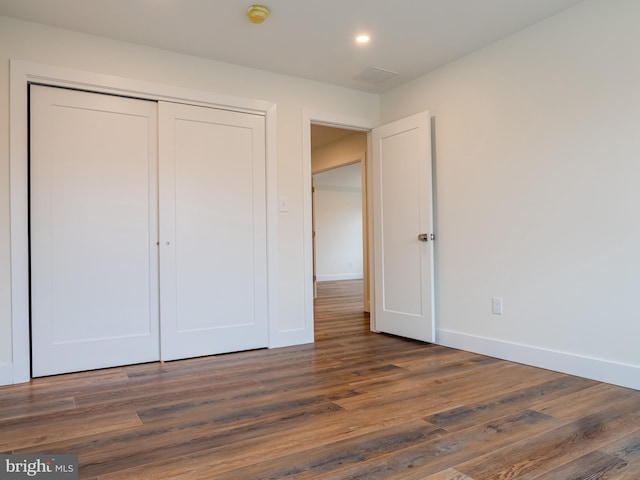 unfurnished bedroom featuring recessed lighting, wood finished floors, baseboards, and a closet