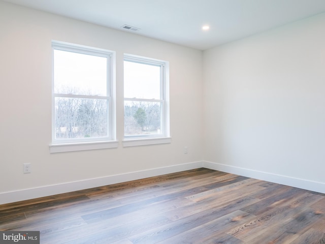 spare room with dark wood-type flooring, recessed lighting, baseboards, and visible vents