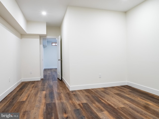 spare room featuring baseboards and dark wood-type flooring