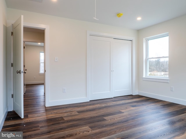 unfurnished bedroom with dark wood finished floors, recessed lighting, a closet, and baseboards