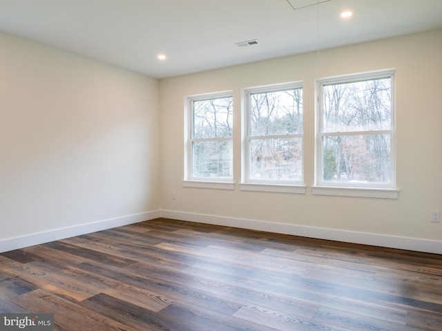 spare room with baseboards, plenty of natural light, attic access, and dark wood-style flooring