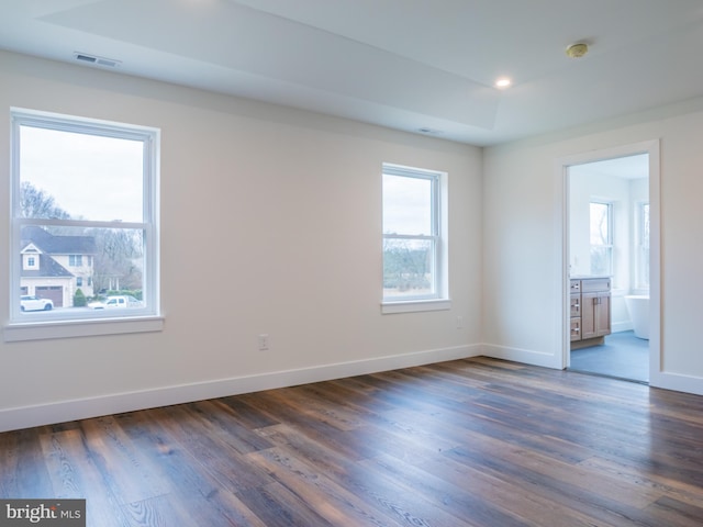 unfurnished bedroom with visible vents, baseboards, dark wood-style floors, and ensuite bathroom