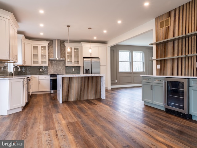 kitchen with stainless steel appliances, decorative backsplash, light countertops, wine cooler, and wall chimney exhaust hood