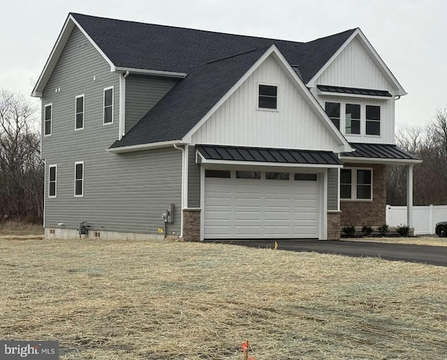 view of front of home featuring a standing seam roof, stone siding, board and batten siding, a shingled roof, and metal roof