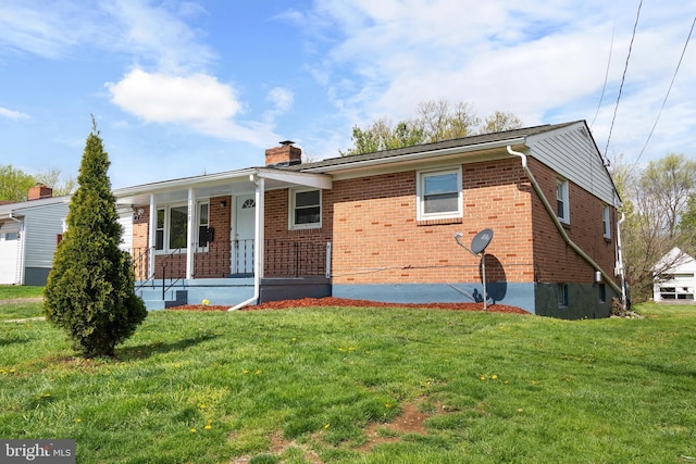 view of front of house featuring a front yard, brick siding, a chimney, and covered porch