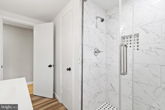 full bath featuring a stall shower, wood finished floors, vanity, and baseboards