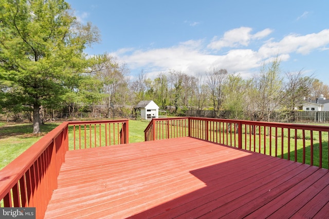 deck with an outbuilding, a fenced backyard, a storage unit, and a lawn
