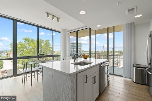 kitchen with dishwasher, expansive windows, visible vents, and a sink