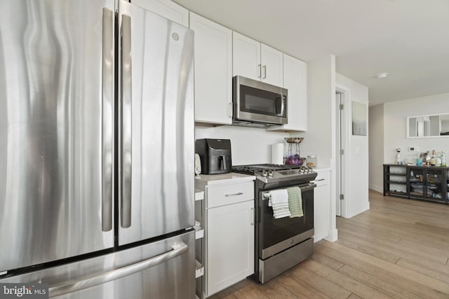 kitchen with light wood-style flooring, white cabinetry, stainless steel appliances, light countertops, and baseboards