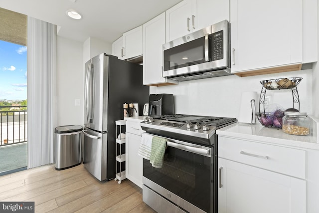 kitchen with light wood finished floors, white cabinetry, recessed lighting, stainless steel appliances, and light countertops