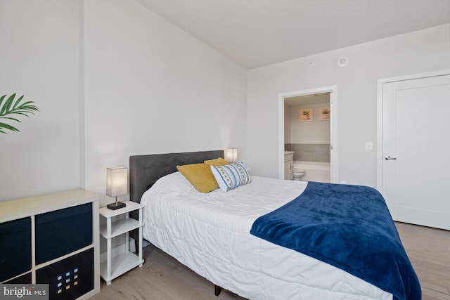 bedroom featuring wood finished floors and ensuite bathroom