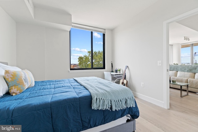 bedroom featuring light wood-style flooring, multiple windows, and baseboards