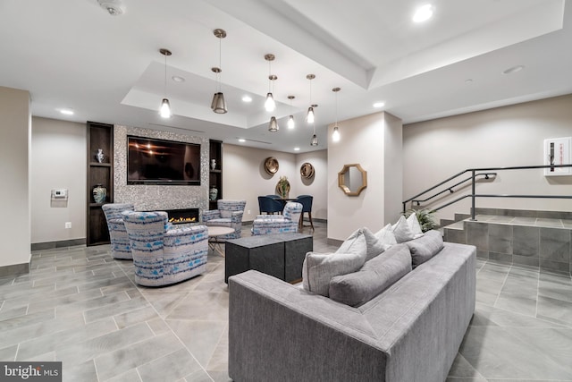 living room with recessed lighting, a fireplace, baseboards, and a tray ceiling
