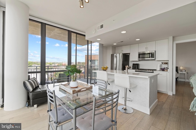 dining space with light wood-type flooring, expansive windows, visible vents, and recessed lighting