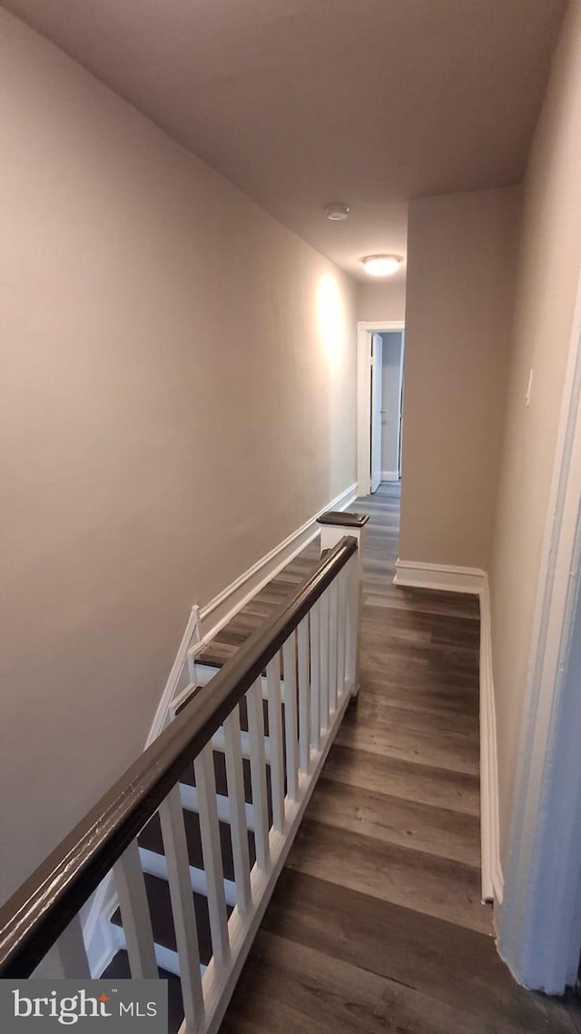 staircase featuring baseboards and wood finished floors