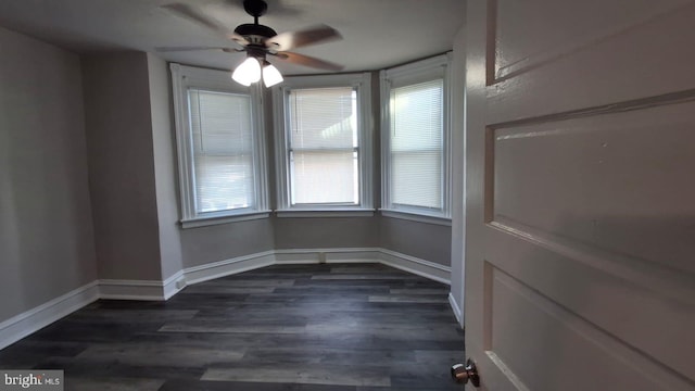 unfurnished room featuring dark wood finished floors, baseboards, and ceiling fan