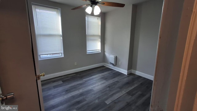 spare room with baseboards, a ceiling fan, and dark wood-style flooring