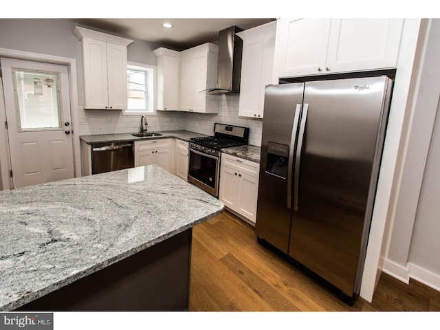 kitchen featuring dark wood-type flooring, appliances with stainless steel finishes, white cabinetry, wall chimney exhaust hood, and a sink