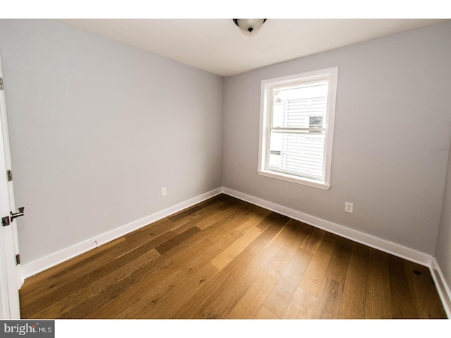 spare room with hardwood / wood-style flooring and baseboards