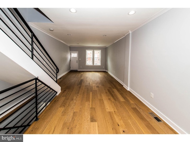 interior space with visible vents, wood finished floors, crown molding, and stairway