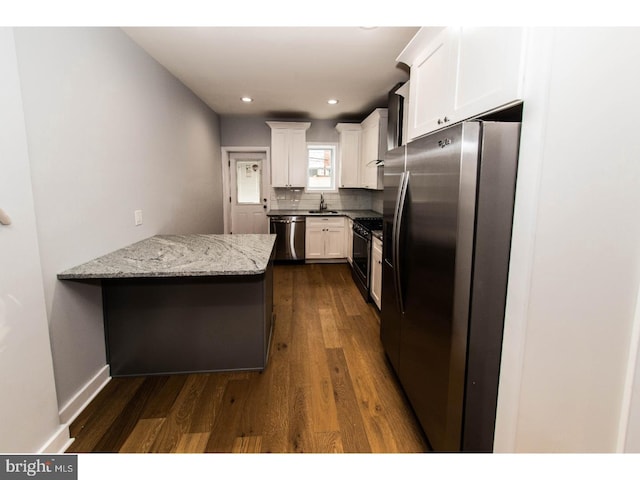 kitchen with dark wood-type flooring, decorative backsplash, appliances with stainless steel finishes, a peninsula, and white cabinets