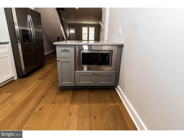 kitchen with light stone counters, baseboards, dark wood-style flooring, and appliances with stainless steel finishes