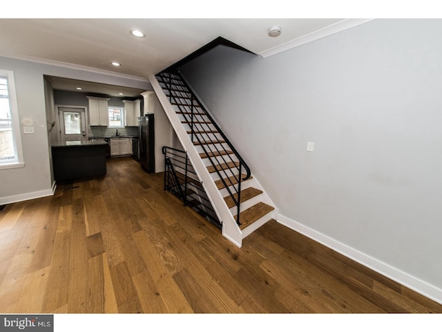 stairway featuring recessed lighting, crown molding, baseboards, and wood finished floors